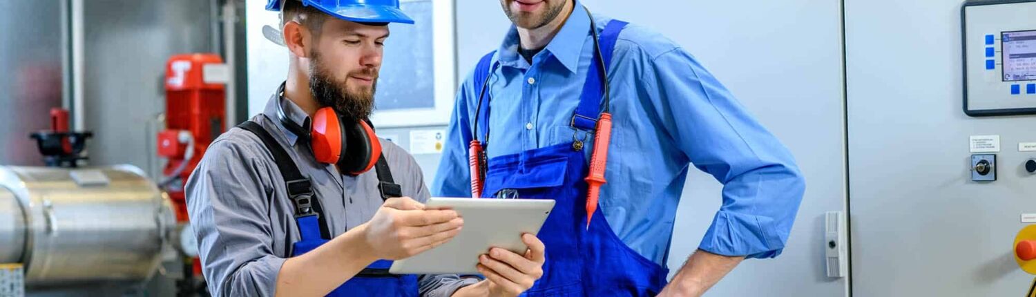 Two-maintenance-workers-looking-over-a-tablet