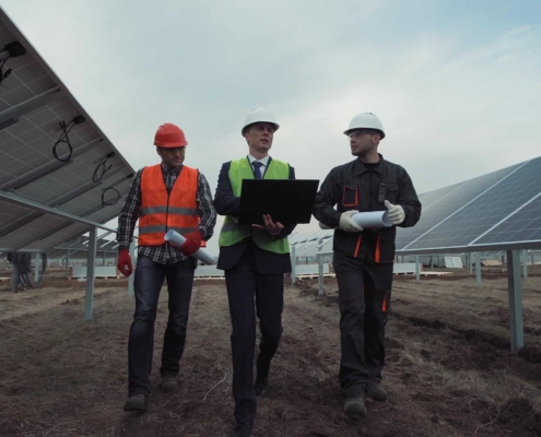 Image of workers walking through a solar farm with a laptop.